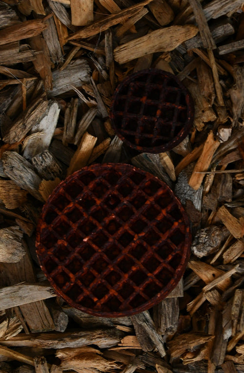 Two camel collagen waffles in different sizes, one larger and one smaller, shown on a natural wood-chip background.