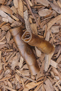 Two natural camel skin rolls with a textured surface, lying on a bed of rustic wood chips.
