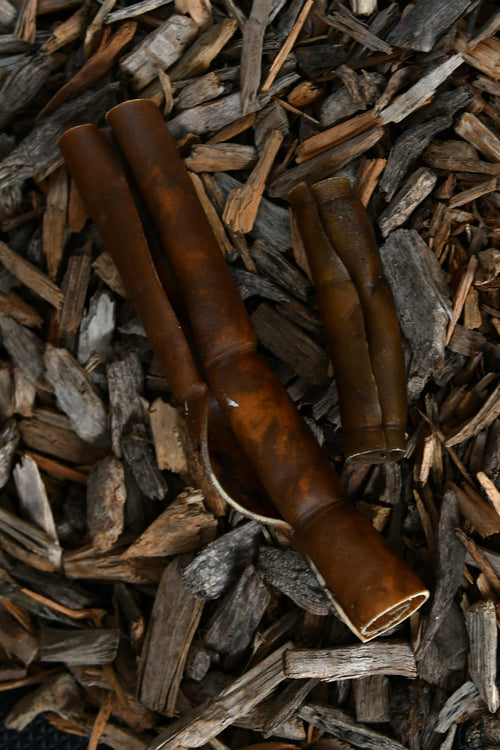 Camel skin rolls in medium and large sizes lying on a bed of wood chips.
