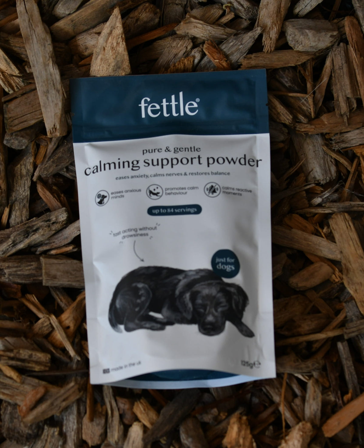 calming support powder for dogs in white and blue packaging on natural wood chips