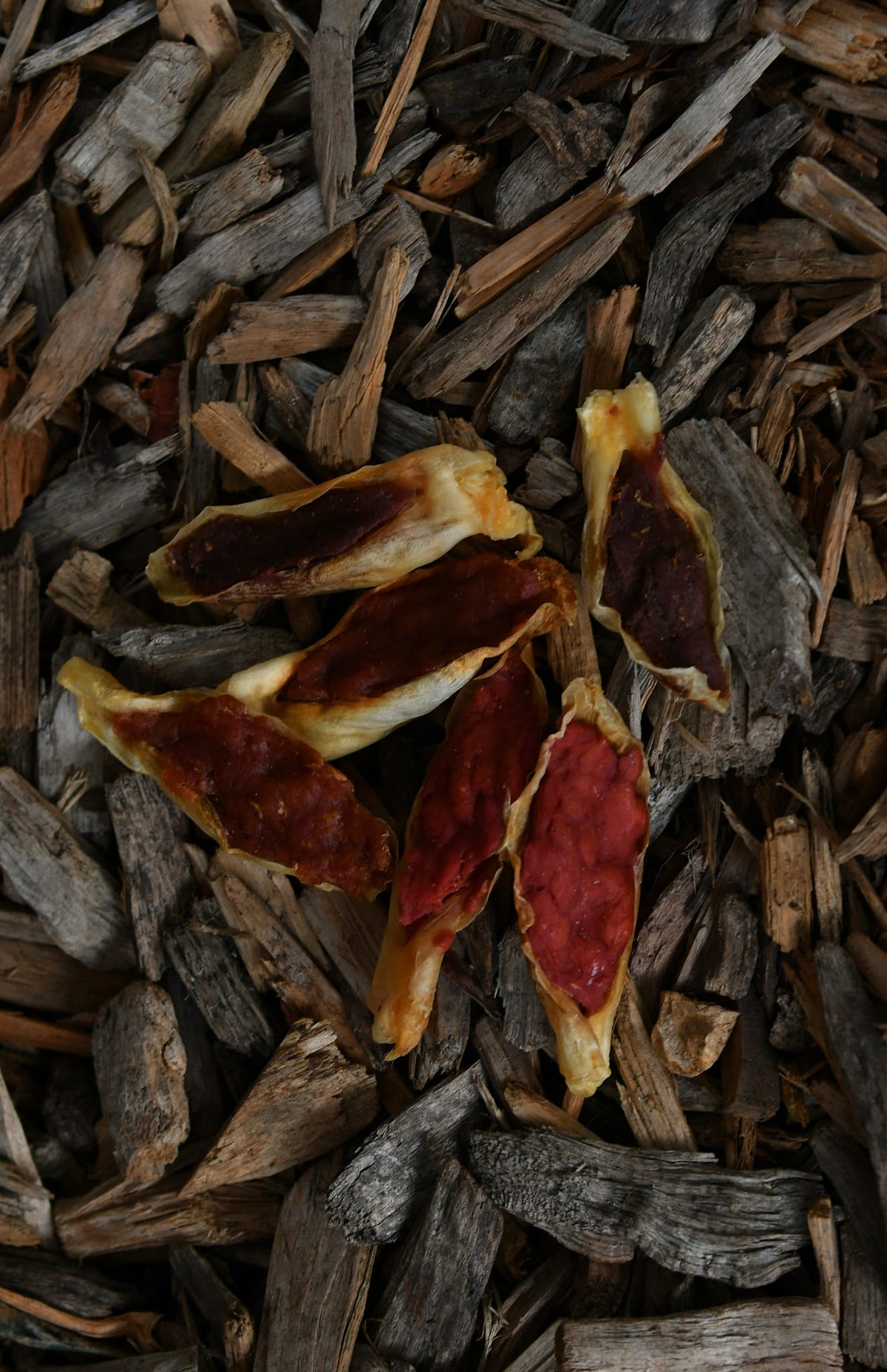 Filled rabbit ears with a meaty filling, displayed on a bed of natural wood chips.