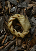 Lamb collagen ring chew displayed on a bed of natural wood chips.