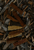 Assorted dried meat strips in various flavours, shown in different colours and textures on a bed of natural wood chips.