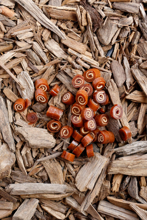 Meat and fish swirls dog treats on natural wood chips