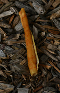 Pork skin roll dog chew on a natural wood-chip background.