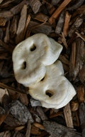 Two white puffed snout chews with rounded shapes and natural openings, shown on a natural wood-chip background.