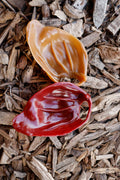 Peanut butter and smoked flavour veggie pig ear dog treats, displayed on a bed of natural wood chips