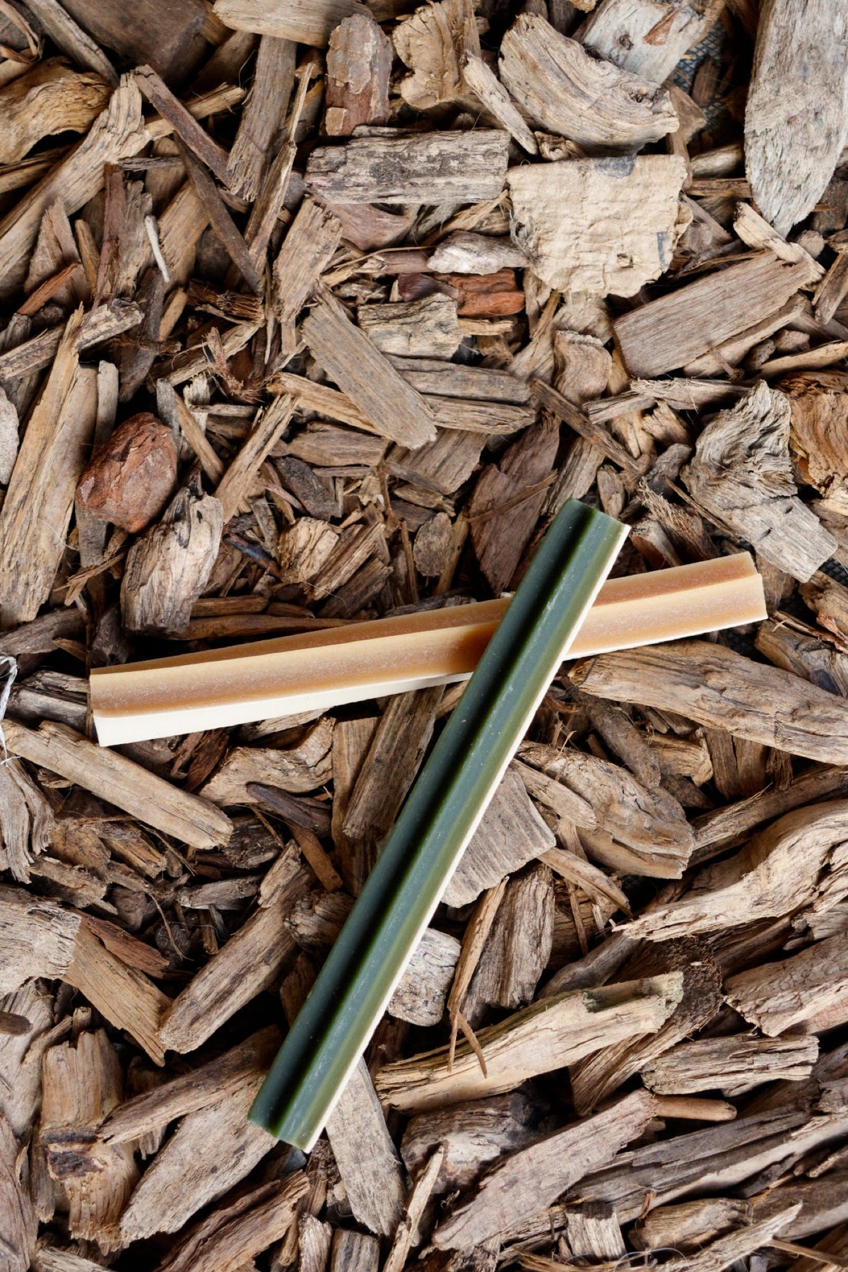 Veggie Star Sticks in Smoked BBQ, Minty Fresh and Peanut Butter flavours, shown on a bed of natural wood chips.